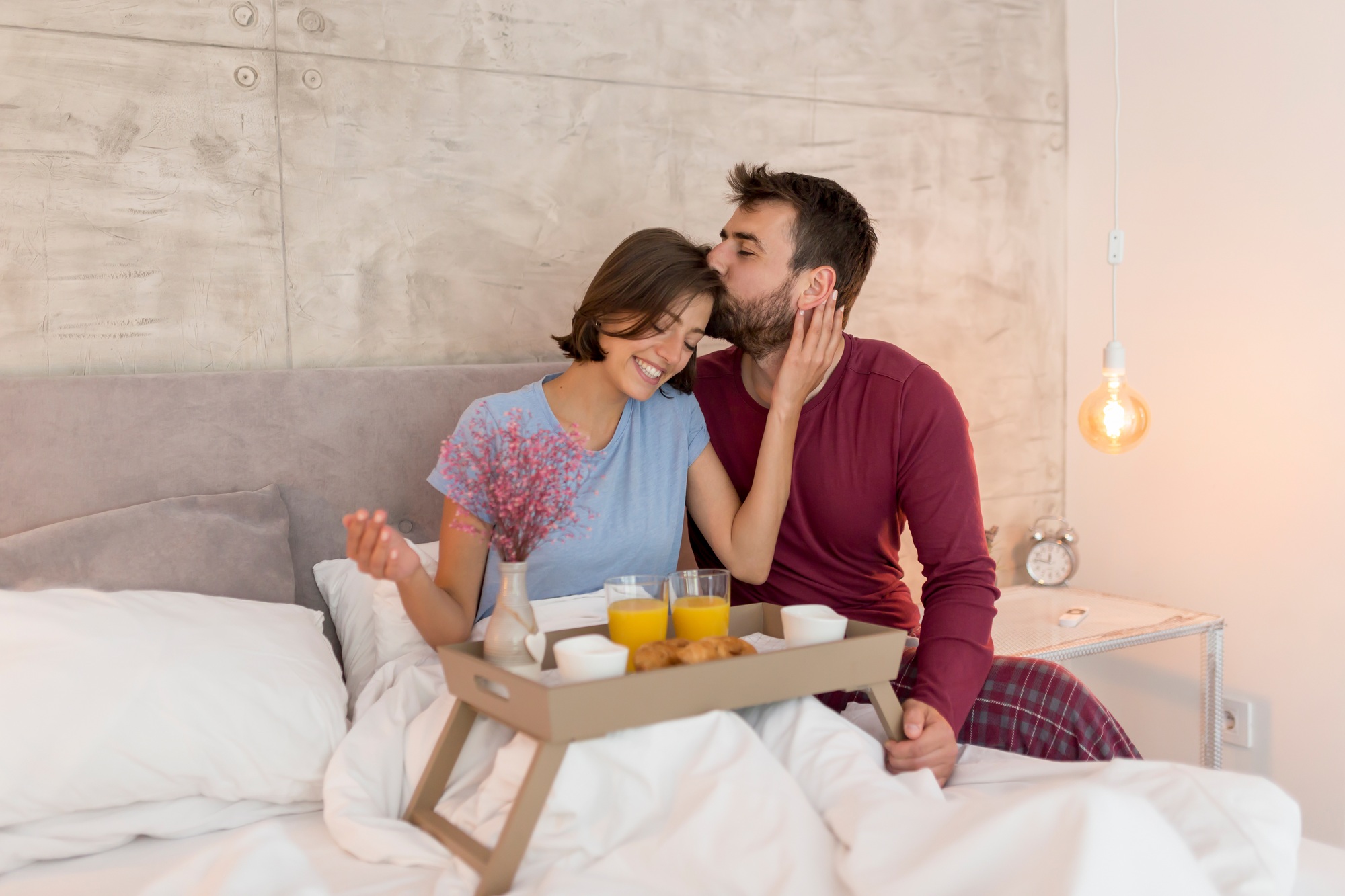 Man bringing a surprise breakfast in bed to woman